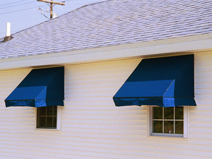 Dark blue awnings over single windows on a white house